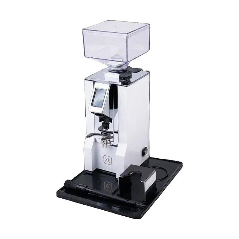 A white and black commercial espresso grinder with a clear hopper on top, shown on a black background with its black accessory base and small black device beside it.