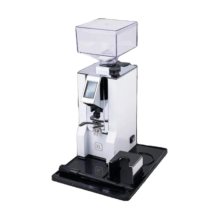 A white and black commercial espresso grinder with a clear hopper on top, shown on a black background with its black accessory base and small black device beside it.